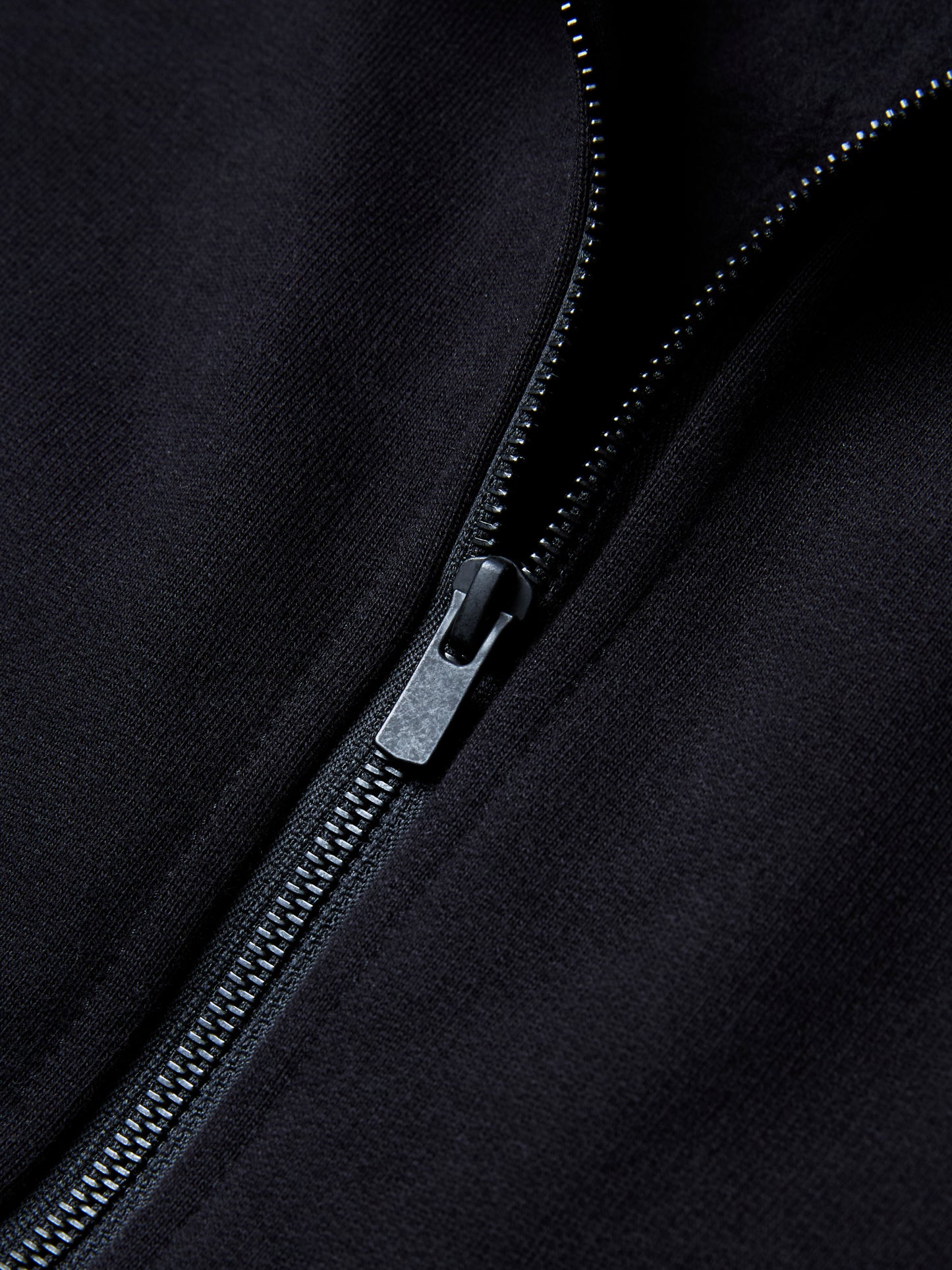 The RIGEL hoodie from PALKAN, a custom designed full-zip hoodie with wrist and shoulder pleats, zoomed in on the black metal zip